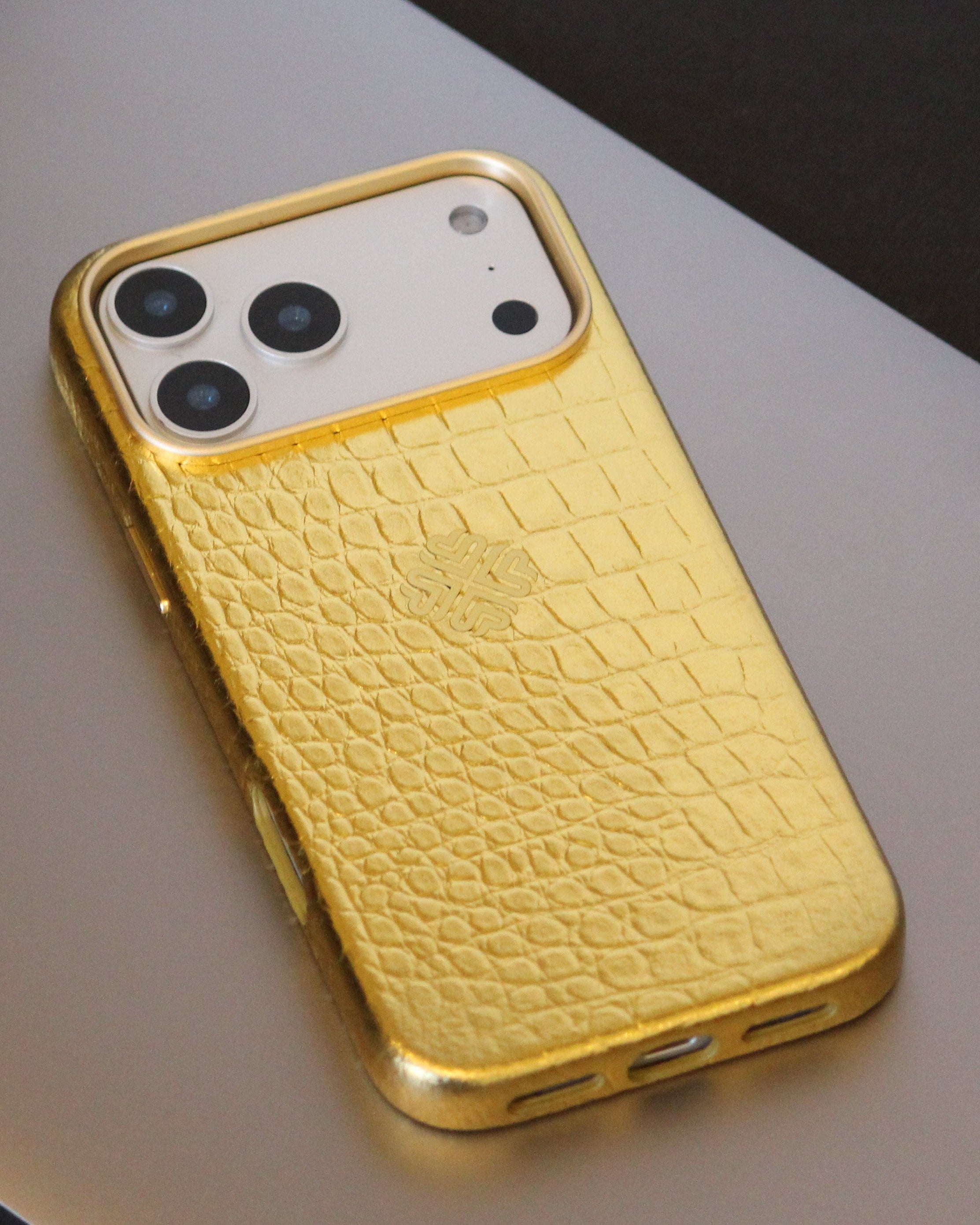 Gold phone case with crocodile texture on a light gray surface