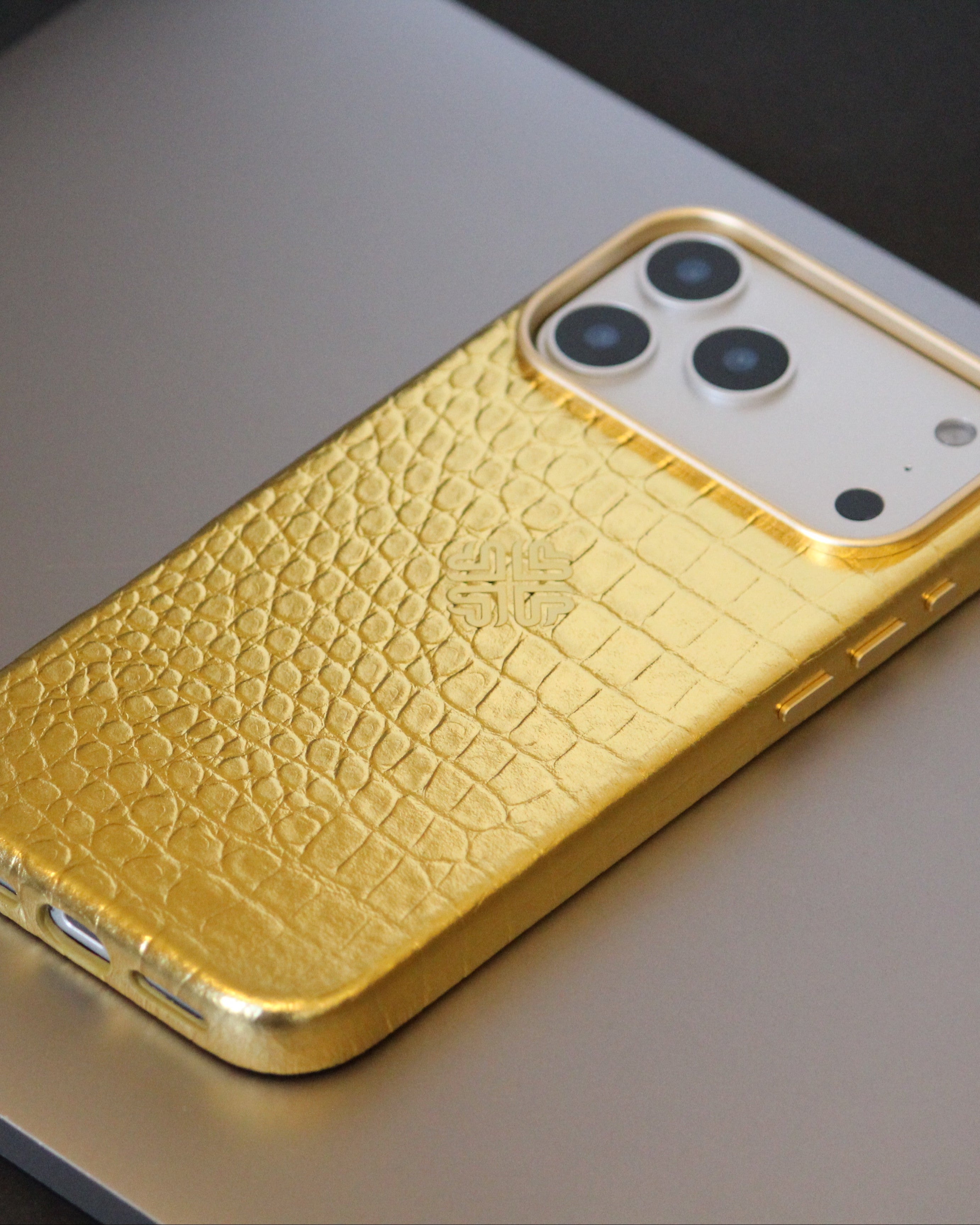 Gold phone case with crocodile texture on a metallic surface