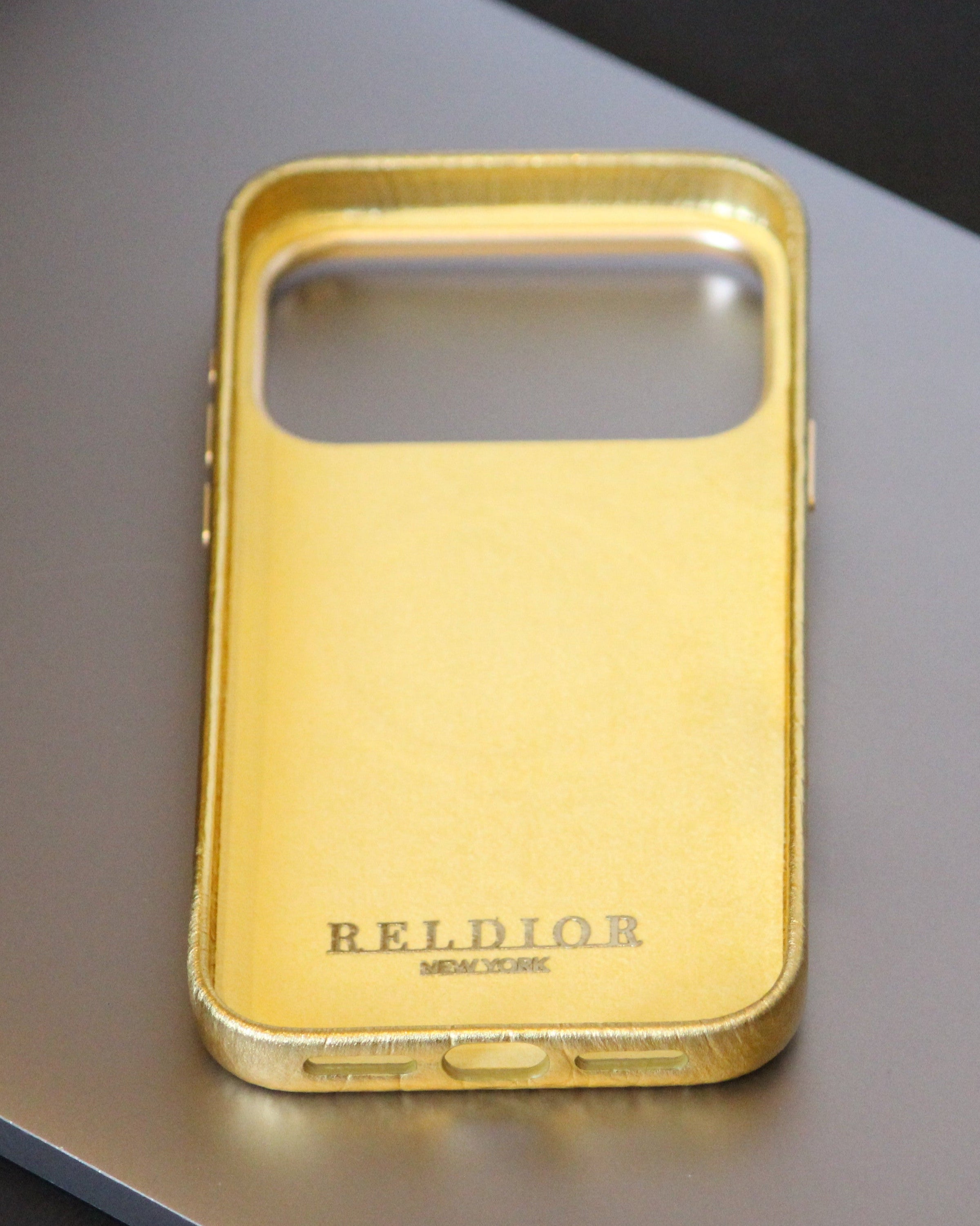 Gold phone case with 'RELIOR' branding on a reflective surface