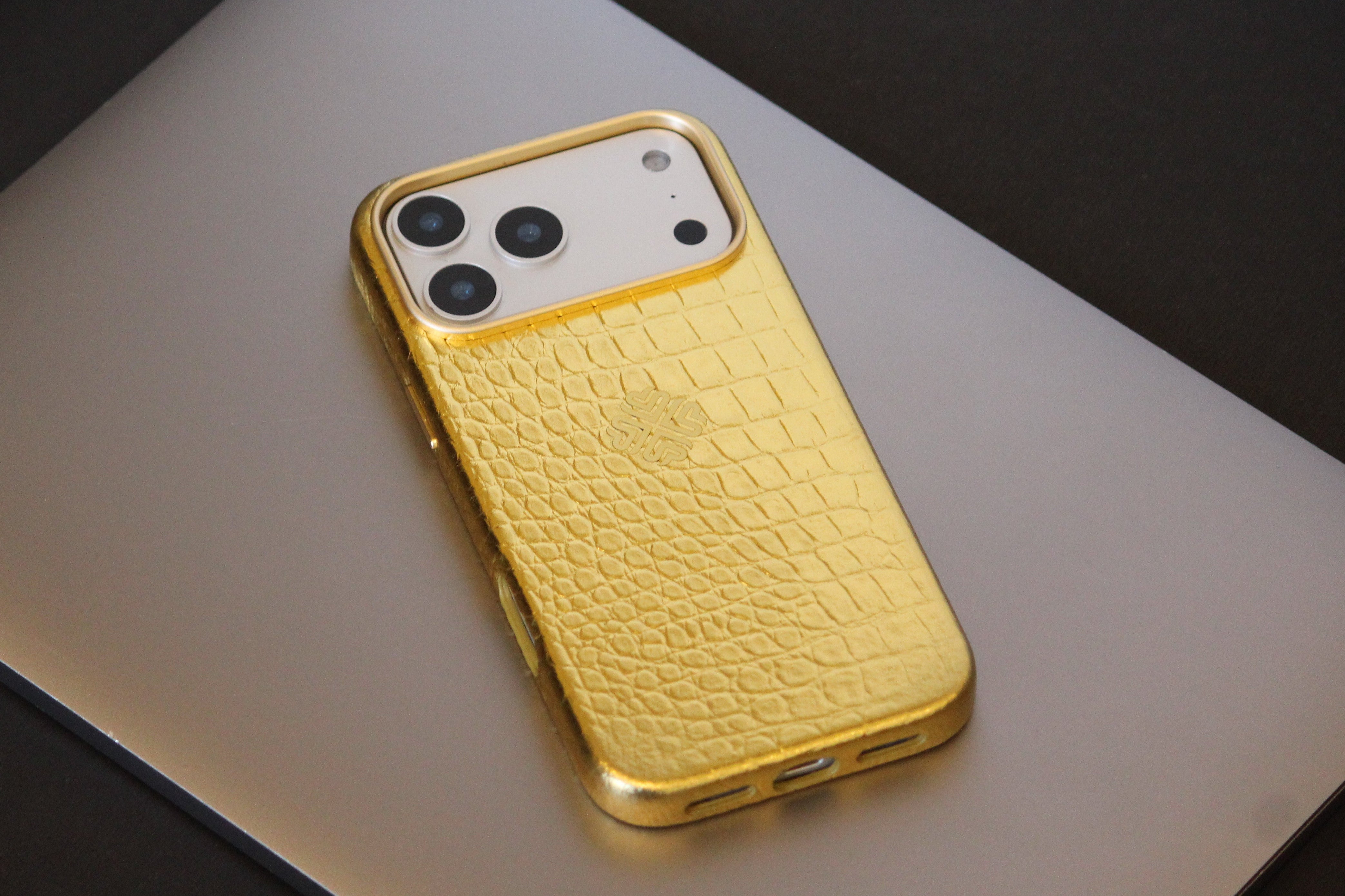 Gold phone case with crocodile texture on a light gray surface